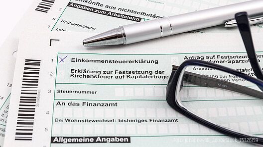 Gewerkschaftsbeiträge absetzbar: Ab 2026 zusätzlich zum Arbeitnehmer-Pauschbetrag Formular Einkommensteuererklärung mit Kugelschreiber und Brille